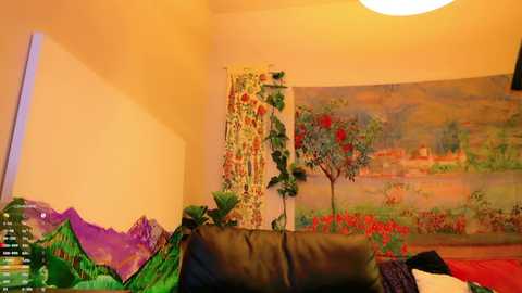 Media: Video of a cozy bedroom with a green and purple bedspread, a black leather couch, a vibrant garden mural, and a white ceiling light.