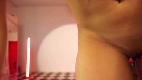 Media: A video showing a close-up of a woman's upper thigh, emphasizing her smooth, light skin. In the background, there's a white wall with a red arch, and a pink curtain.