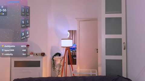 Media: Video of a modern, minimalist bedroom featuring a projector screen displaying a soccer match, a tall lamp, and a closed door.