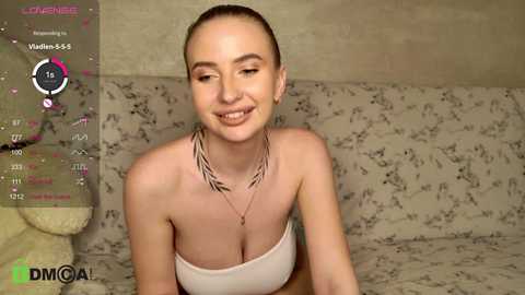 Media: Video of a fair-skinned woman with short, dark hair, wearing a strapless white top, smiling, on a floral-patterned couch, overlaid with a virtual reality interface.