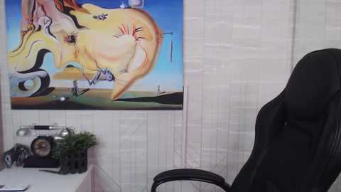 Media: Video of an office with a large, abstract painting of a figure on a white wall. A black ergonomic chair sits in the foreground.