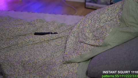 Media: Video of a green and white striped blanket with a black knife handle sticking out, laying on a grey couch, with a purple glowing light in the background.