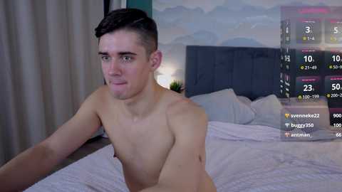 Media: Video of a shirtless, fit young man with short brown hair, lying on a bed with white sheets. Background features a digital display with live-stream stats and a cloud mural.