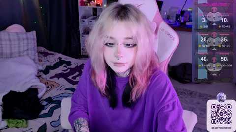 Media: Video of a young woman with long, multicolored hair, wearing a purple sweatshirt, sitting in a gaming chair. Background shows a cluttered bedroom with gaming equipment and a bed.