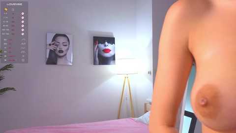 Media: Video of a nude woman with medium-sized breasts, standing in a modern bedroom with white walls, a pink bed, and a white lampshade.