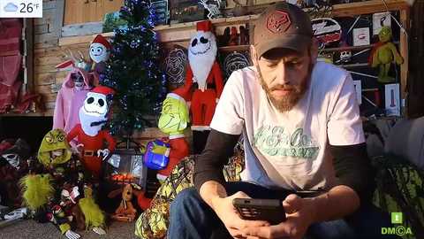 Media: Video of a bearded man in a white t-shirt and baseball cap, sitting on a couch, holding a smartphone, surrounded by colorful Christmas decorations including Jack Skellington figures and a lit tree.