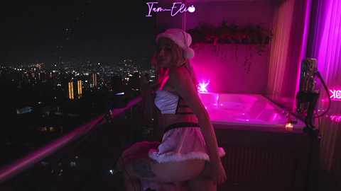 Media: A video of a woman in a white hat and lingerie, standing on a balcony at night, illuminated by pink lights.