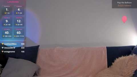 Media: A video of a cozy living room with a dark blue couch, light pink throw blanket, and a fluffy beige pillow, illuminated by soft lighting.