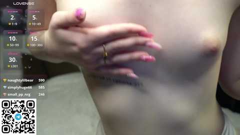 Media: Video of a light-skinned, topless woman with pink nails, covering her small breasts with one hand. Background shows a digital interface with statistics and a QR code.