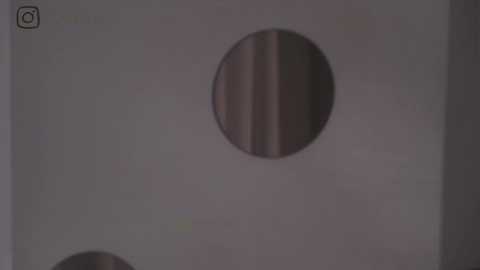 Media: A video of a large, round hole in a white wall, with a blurry, partially visible person's face and body in the background, suggesting an escape attempt.