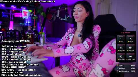 Media: Video of a woman in a My Melody pajama set, sitting at a desk with various drinks, in a dimly lit room, with a screen displaying her social media stats.