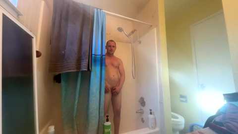 Media: Video of a naked, overweight, bald man standing in a small, beige-tiled bathroom with a shower curtain partially open.