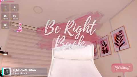 Media: Video of a modern living room with a white armchair, pink floral artwork, and \"Be Right Back\" text overlaid in a playful, soft pink brushstroke.