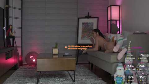 Media: Video of a woman in lingerie on a sofa, text overlay, dimly lit room with modern decor, pink light, and a digital screen with video stats.