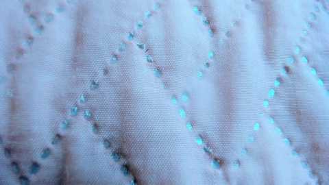 Media: Video of a close-up of a delicate, sheer white fabric adorned with small, scattered light blue sequins. The fabric has a textured, slightly wrinkled appearance, giving it a soft, luxurious feel.