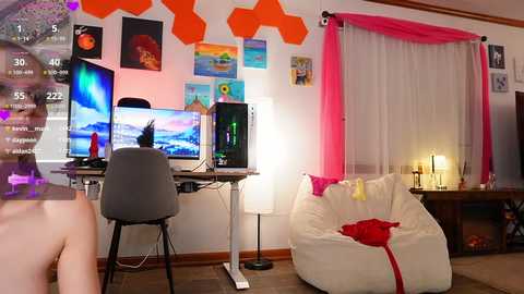 Media: A brightly lit, modern bedroom with a white beanbag, two desks, a gaming monitor, and colorful wall art.