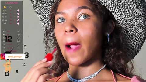 Media: Video of a light-skinned Black woman with curly hair, wearing a white cowboy hat and red lipstick, applying it with a brush. Calendar with red lipstick icon on left.