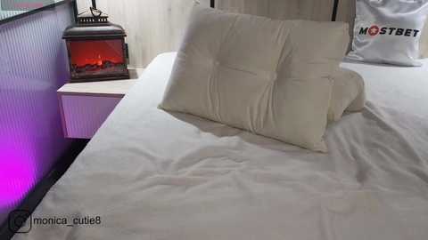 Media: A video of a neatly made bed with white sheets and a decorative lantern emitting a warm glow on a wooden nightstand.