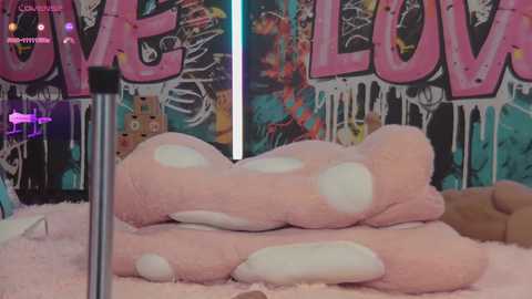 Media: A video of a pink, polka-dotted furry object resembling a large, fluffy penis, with a background featuring graffiti-style text reading \"LOVE.\