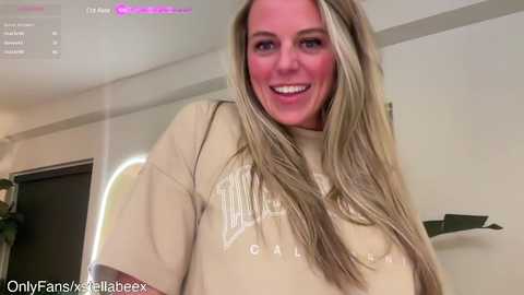 Media: A video of a smiling, light-skinned, blonde woman wearing a beige California State University T-shirt. Background shows a modern, indoor setting with beige walls and a green plant.