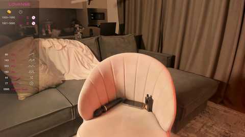 Media: A video of a modern living room with a beige, curved chair, gray couch, and beige curtains; a VR headset is placed on the chair.