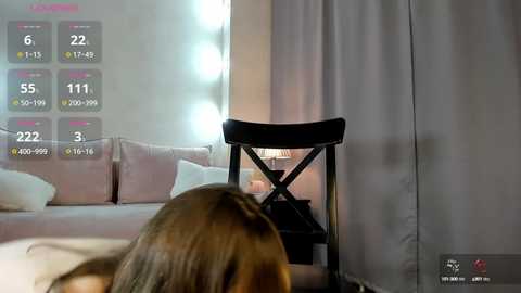 Media: A video of a woman with brown hair in a salon chair, surrounded by soft pink and white pillows, with a lit vanity mirror in the background.