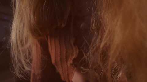 Media: Video of a close-up of a person's face with long, wavy, light brown hair, showing a distressed expression with eyes closed and hands covering their face, set against a dark, blurred background.