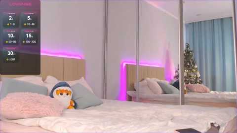 Media: Video of a modern bedroom with a plush, white bed adorned with pillows, a stuffed animal, and a Christmas tree reflected in a mirror. Purple LED lights illuminate the room, creating a cozy atmosphere.