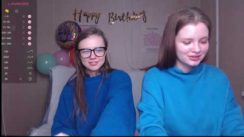 Media: Video of two young women in blue shirts, smiling, in a birthday-themed room with a \"Happy Birthday\" sign and colorful balloons.