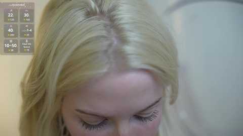 Video of a young blonde woman with shoulder-length hair, looking downward, with a scientific chart displaying hair growth statistics in the background.