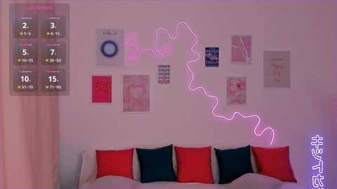 Media: Video of a modern bedroom with a white wall, pink neon heart-shaped lights, red and dark blue pillows, and colorful posters.