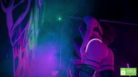 Media: A video captures a woman in a black leather harness, gagged, with glowing green and purple lights, and a \"DMCA\" watermark in the corner.