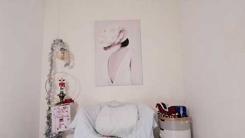 Media: A video of a minimalist room with a cream wall, a large white rose painting, a white chair, and a decorative box with toys.