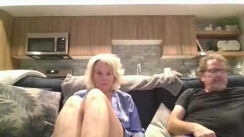 Media: Video of an older couple on a couch in a modern kitchen with light wood cabinets, stainless steel appliances, and a backsplash.