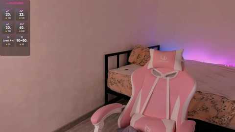 Video of a pink gaming chair with white accents in a minimalist, pink-lit bedroom. A bed with floral bedding is visible in the background, along with a digital clock displaying time and temperature.