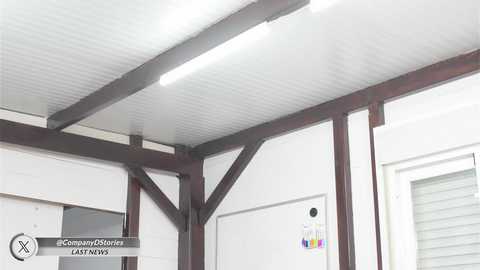 Media: Video of a modern, industrial warehouse interior with white walls, exposed wooden beams, and a fluorescent light fixture on the ceiling.