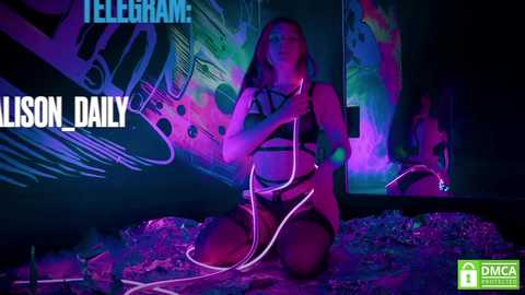 Media: Video of a woman in black lingerie kneeling on a bed, illuminated by neon lights, with graffiti and a \"TELEGRAM\" watermark.