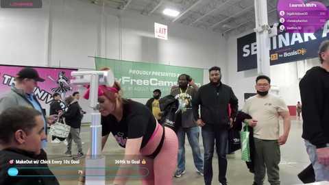 Media: Video of a diverse group of people, predominantly men, gathered in a modern, well-lit room with large banners and signs. Some are wearing sports attire, while others are in casual clothes.