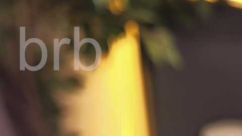 A blurred, soft-focus video with the text \"brrb\" overlaid in the foreground. The background features a warm, yellow light source illuminating a dark, possibly wooden, surface. The image conveys a cozy, intimate atmosphere.