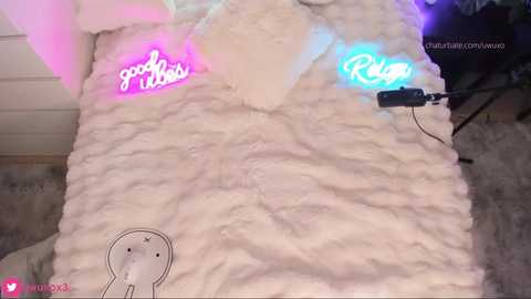 Media: A video of a white furry blanket with neon pink and blue lights spelling \"good vibes\" and \"Riley,\" featuring a cartoon bunny graphic.