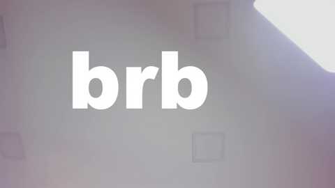 Media: Video of a plain white wall with the word \"brrb\" in bold, white letters. The image is slightly blurry, with a bright light source creating a lens flare in the upper right corner.