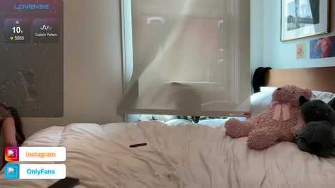 Media: Video of a cozy bedroom with a white bed, teddy bears, and a partially opened window with a sheer curtain. The room has a minimalist decor with framed artwork on the wall.