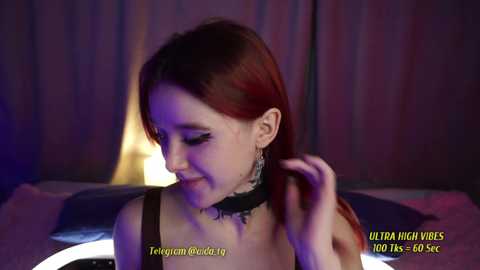 Media: Video of a fair-skinned woman with long red hair, wearing a black choker, smiling and adjusting her hair, in a dimly lit room with purple and blue lighting. Text overlays: \"Ultra High Vires 1080p 60fps 100Kbps\" and \"T\u00e9l\u00e9gram Buc\u00e9 19.\