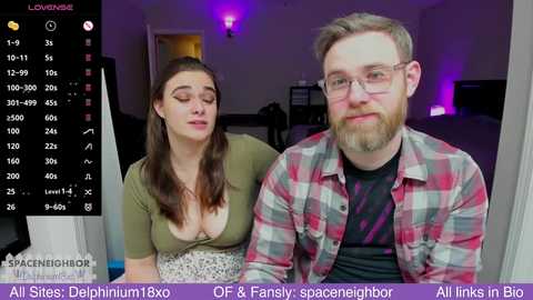 Media: Video of a couple, a woman with long brown hair in a green top and a man with glasses in a plaid shirt, in a dimly lit room with purple lighting and a \"Live\" webcam overlay.