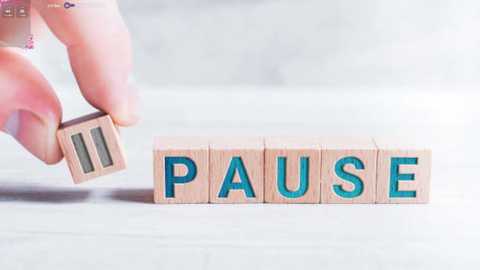 Media: Video of a hand holding a wooden block with the letters \"PAUSE\" in turquoise, placed on a light-colored, textured surface.