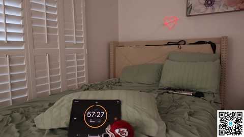 Media: A video of a cluttered, beige-tiled bathroom with a green-tiled shower, a black digital clock showing 7:27, and a red and white football helmet on the floor.