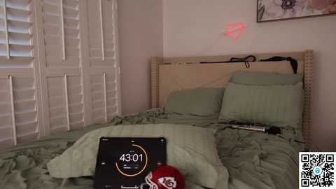 Media: Video of a messy, green-bedroom with a digital clock showing 4:01, a red hat, and a smartphone on a rumpled bed.