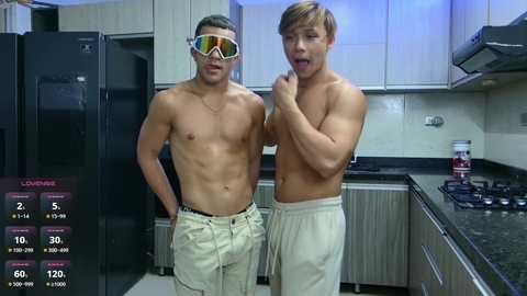 Media: Video of two shirtless Asian men in a modern kitchen, one wearing reflective sunglasses, the other holding a phone. Background features stainless steel appliances and white cabinetry.