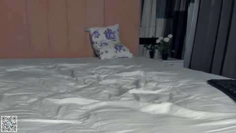 Media: Video of a neatly made bed with white sheets and a floral-patterned pillow, against a pink paneled wall. A black laptop is partially visible on the right.