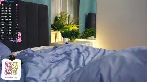 Media: Video of a neatly made bed with blue sheets, a white headboard, and a potted plant. A smartphone with a QR code for \"Drama\" is attached to the headboard.